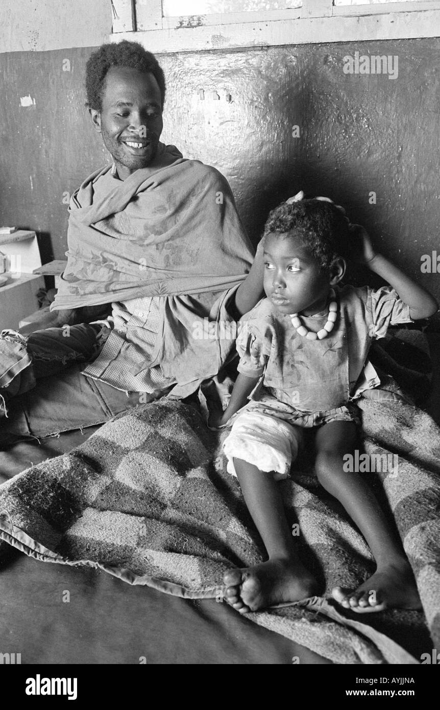 S/W eines Mannes, der mit seiner Tochter in einer ländlichen Krankenstation mit wenigen Einrichtungen in Hararghe sitzt. Äthiopien Stockfoto