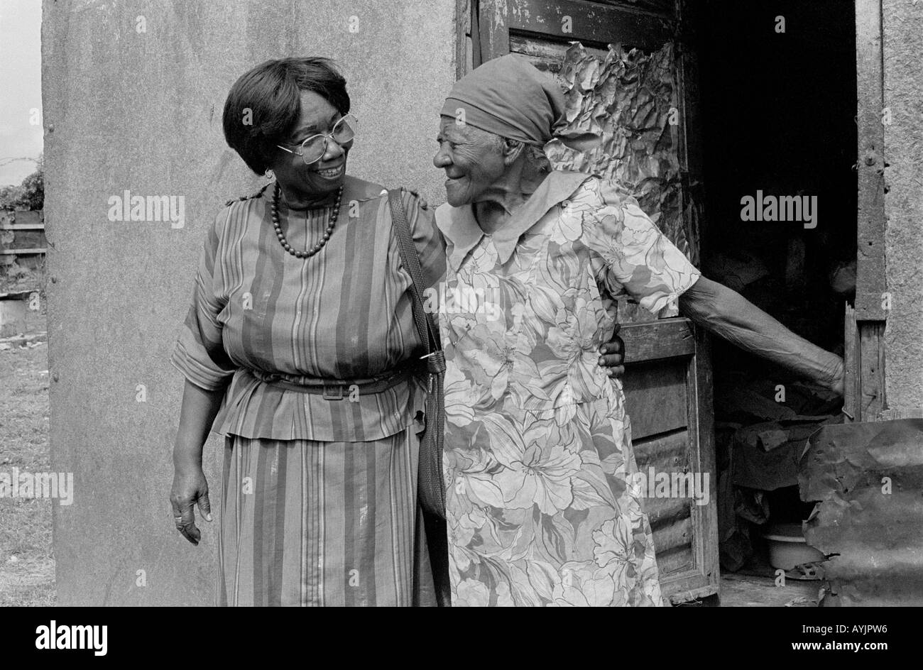 B/W eines Gesundheitsbesuchers von Sozialdiensten, der eine mittellose ältere Frau besucht, die im ärmsten Teil der spanischen Stadt, Jamaika, lebt Stockfoto