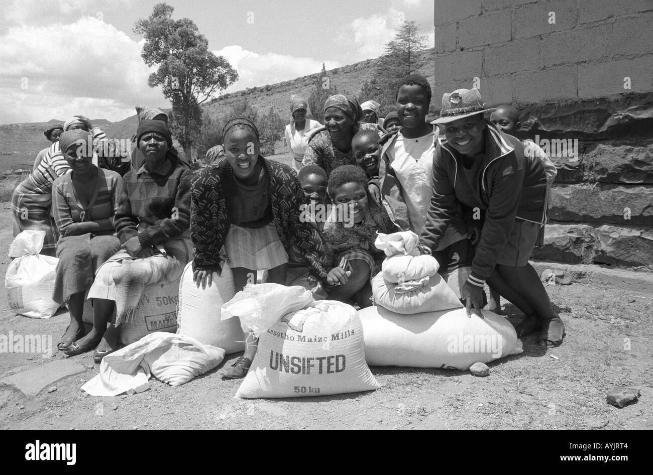 B/W von glücklichen Dorfbewohnern, die während einer längeren Dürreperiode Lebensmittelhilfe für Maismehl erhalten, Lesotho, Südliches Afrika Stockfoto