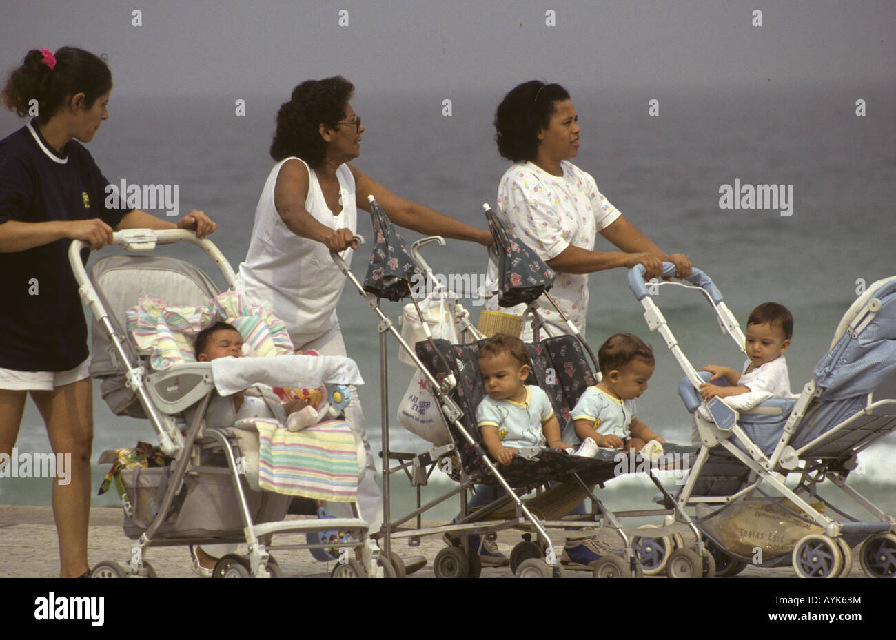 Rio De Janeiro Brasilien drei Dienstmädchen laufen Babys in ihrem Kinderwagen Ipanema Strand. Stockfoto