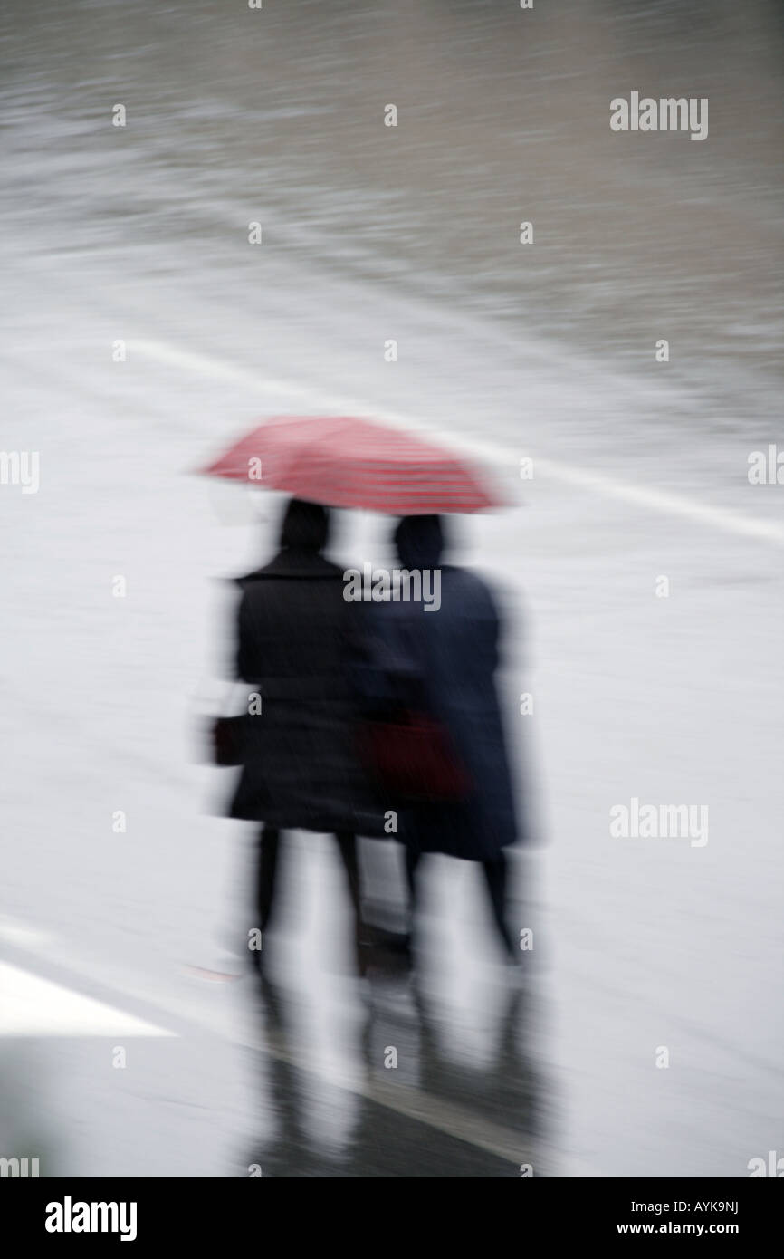 Menschen Kreuzung Straße mit Schirm im Regen Stockfoto