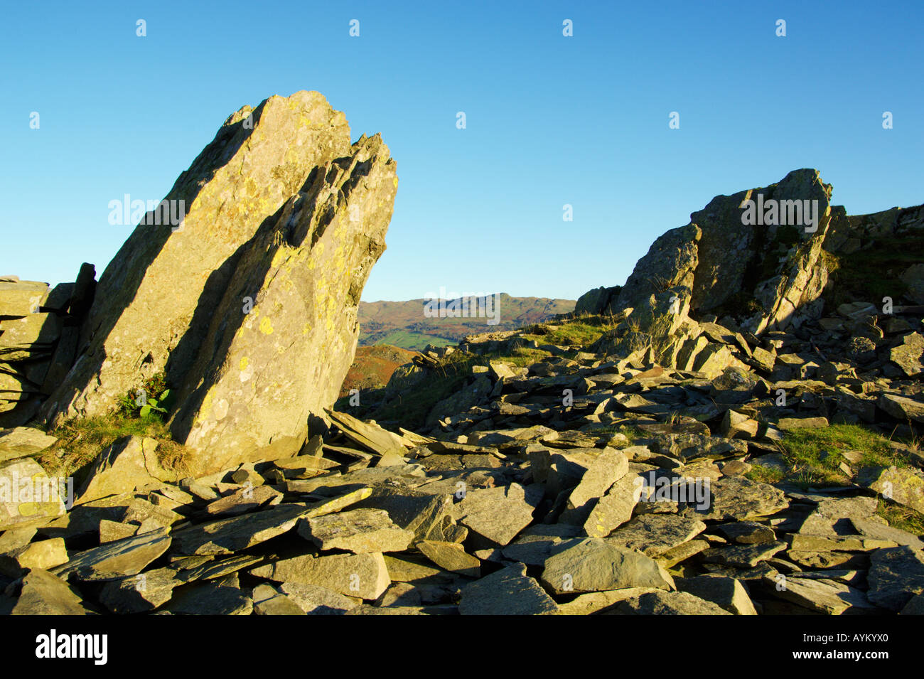 Felsbrocken auf dem Gelände eines alten Steinbruchs auf Loughrigg fiel mit Wansfell Hecht in der Ferne Stockfoto