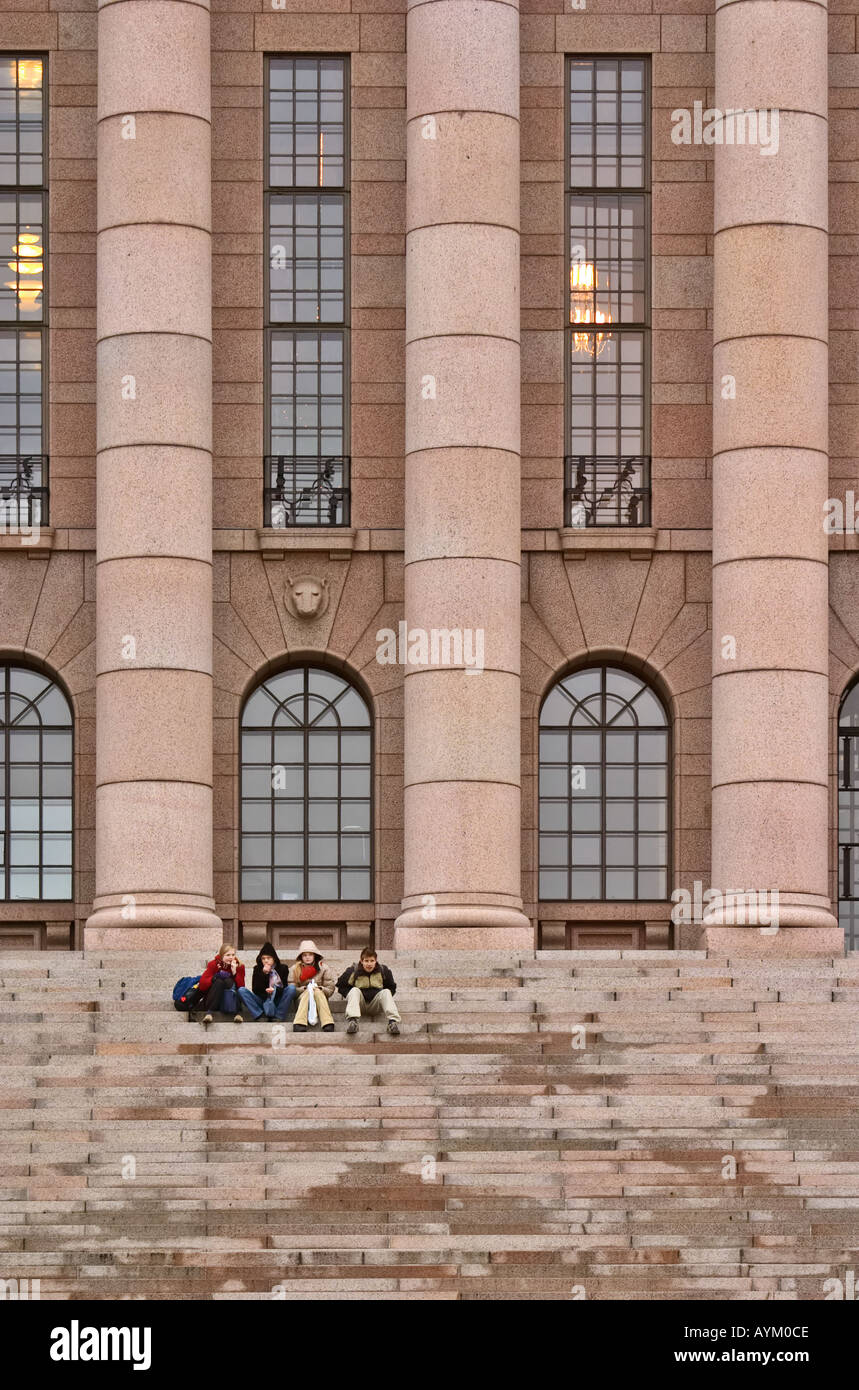 Junge Leute sitzen auf den Stufen des finnischen Parlamentsgebäude, Helsinki, Finnland Stockfoto