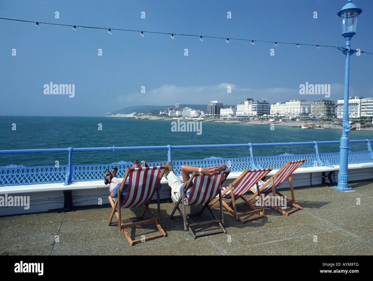 Sitzen in Liegestühlen, Eastbourne Pier, England, an einem heißen Sommertag Stockfoto