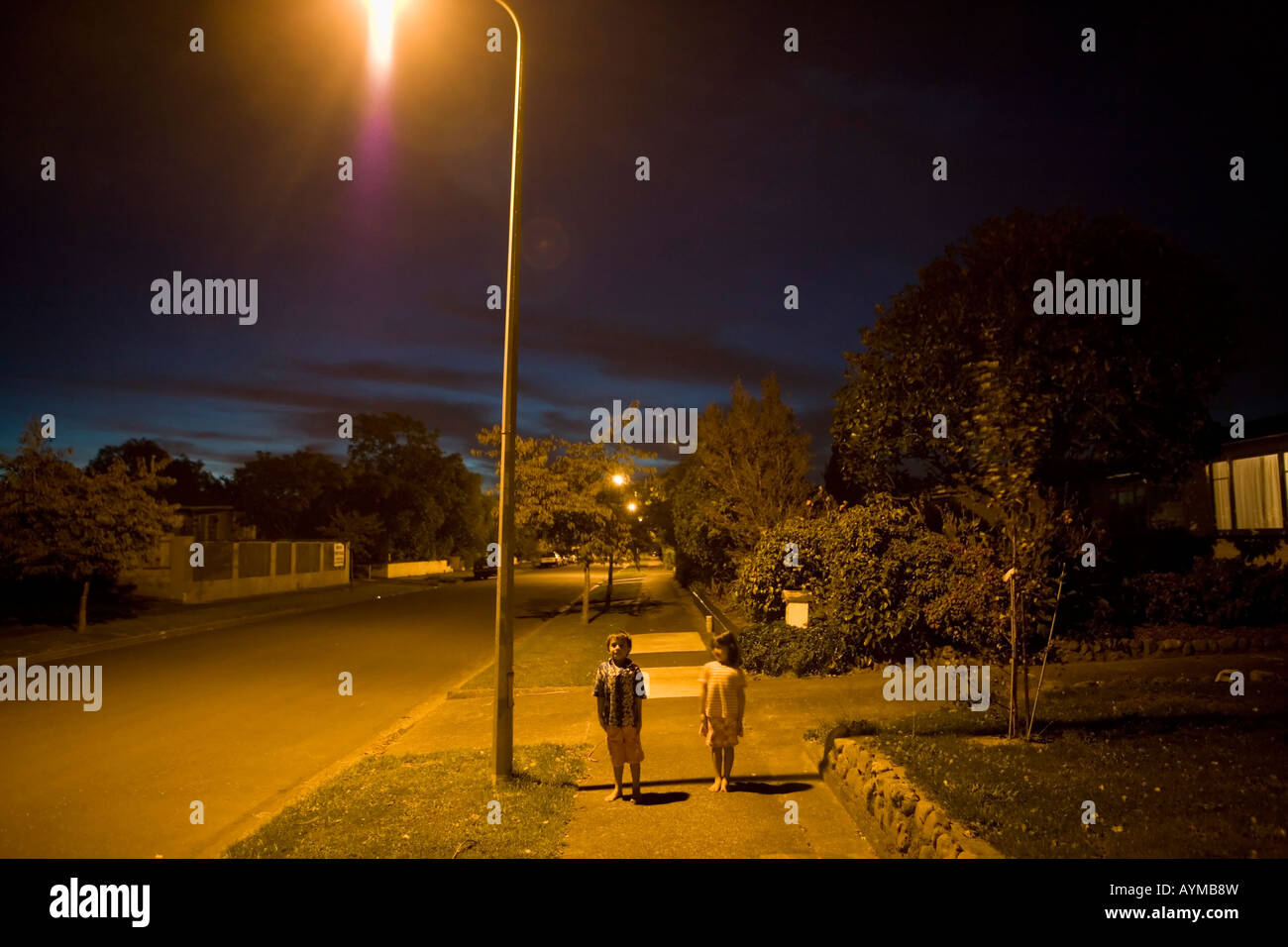 Bruder im Alter von sechs und Schwester im Alter von vier Stand unter Straßenlaterne auf einer öffentlichen Straße in Palmerston North New Zealand Stockfoto