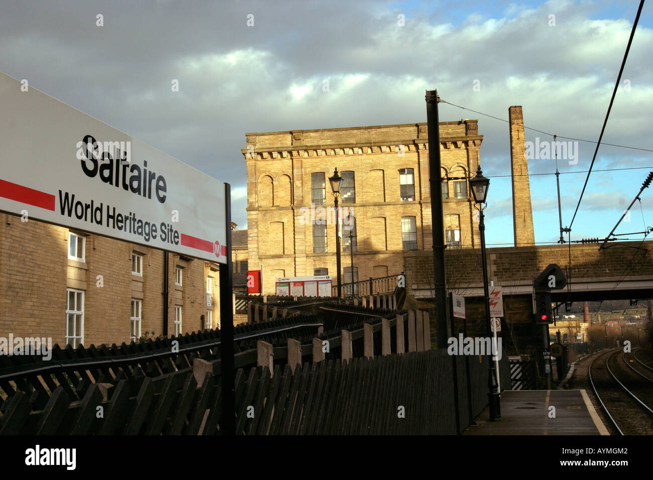 Saltaire World Heritage Site Zeichen unter Angabe oben auf Saltaire Station mit Mühle und Schornstein im Hintergrund Stockfoto