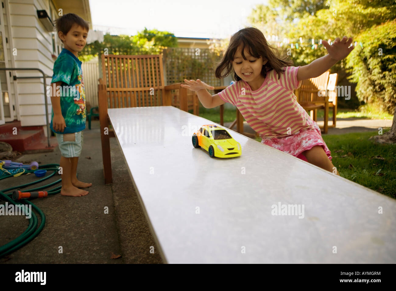 Bruder und Schwester spielen mit Spielzeugautos auf eine hausgemachte schräge Rampe, die Mädchen im Alter von sechs jungen im Alter von vier Jahren Stockfoto