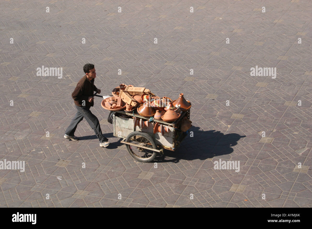 Mann, Schieben Karren von Tajine Töpfen über den Jemaa El Fna Platz in Marrakesch Stockfoto