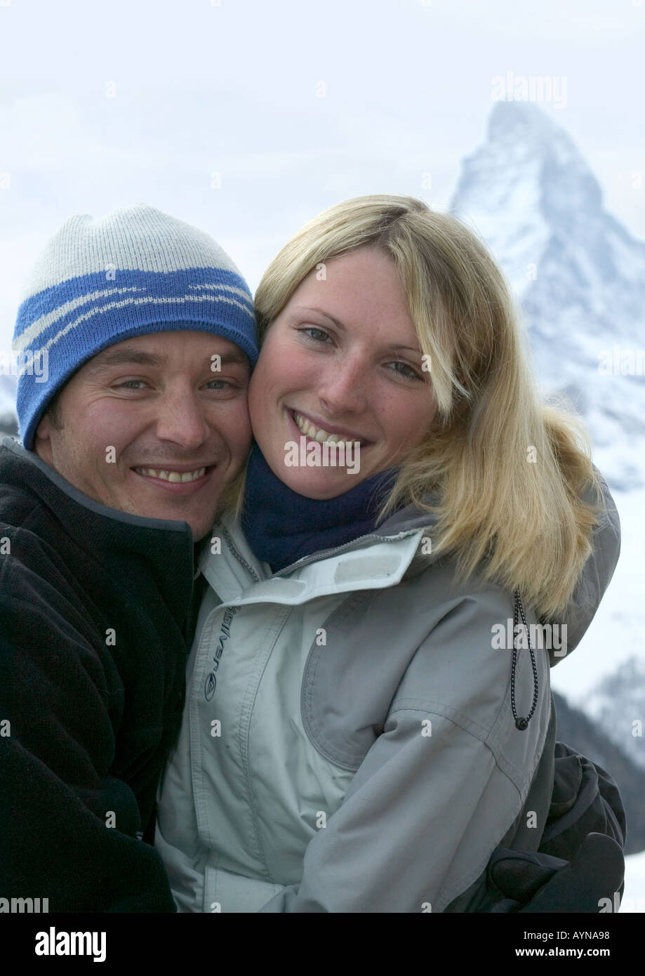junges Paar entspannt und lächelnd auf Skipisten mit Blick auf Stockfoto