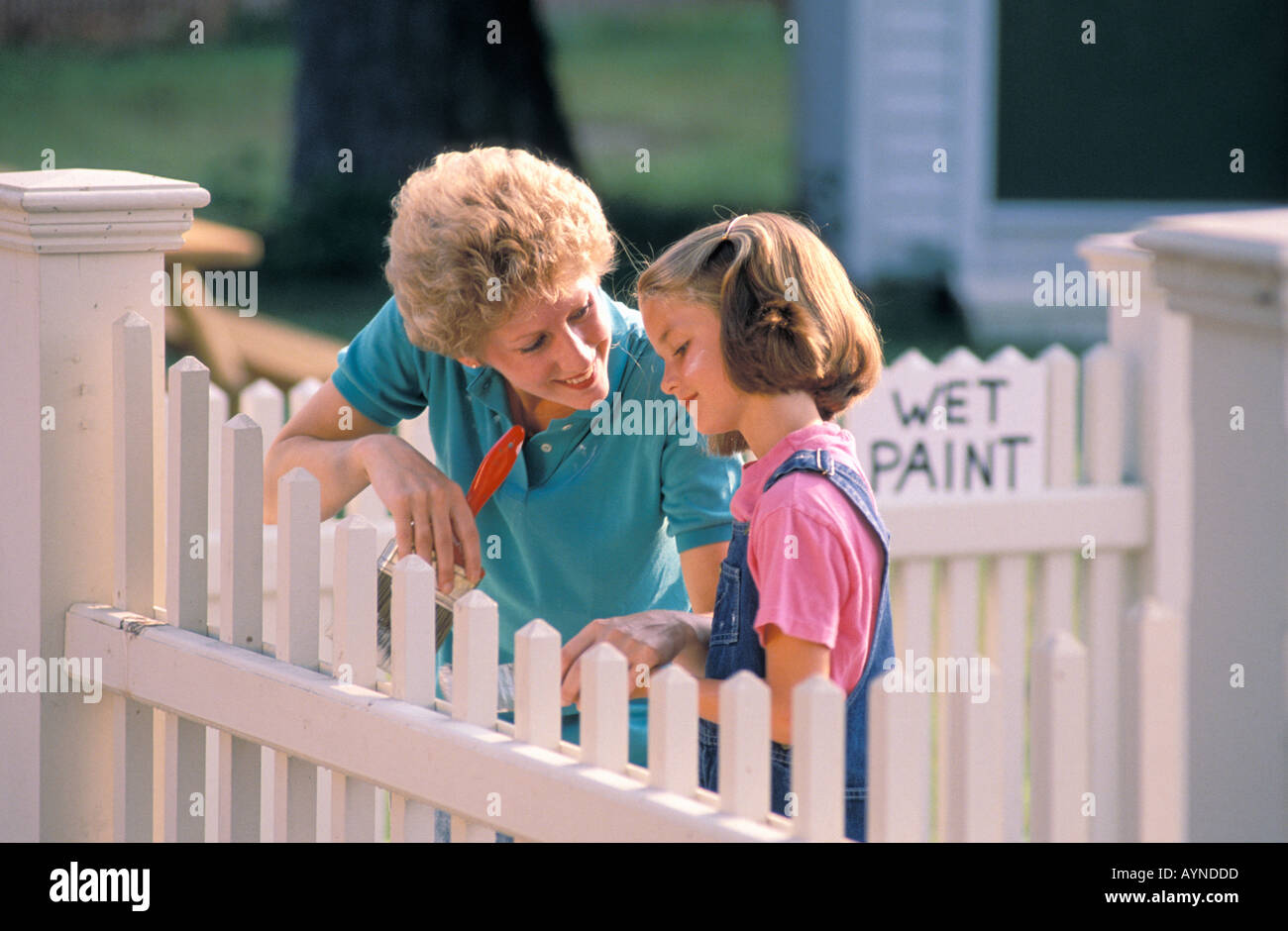 Kaukasischen Mutter und Tochter Malerei eine weiße Pickett Zaun Stockfoto