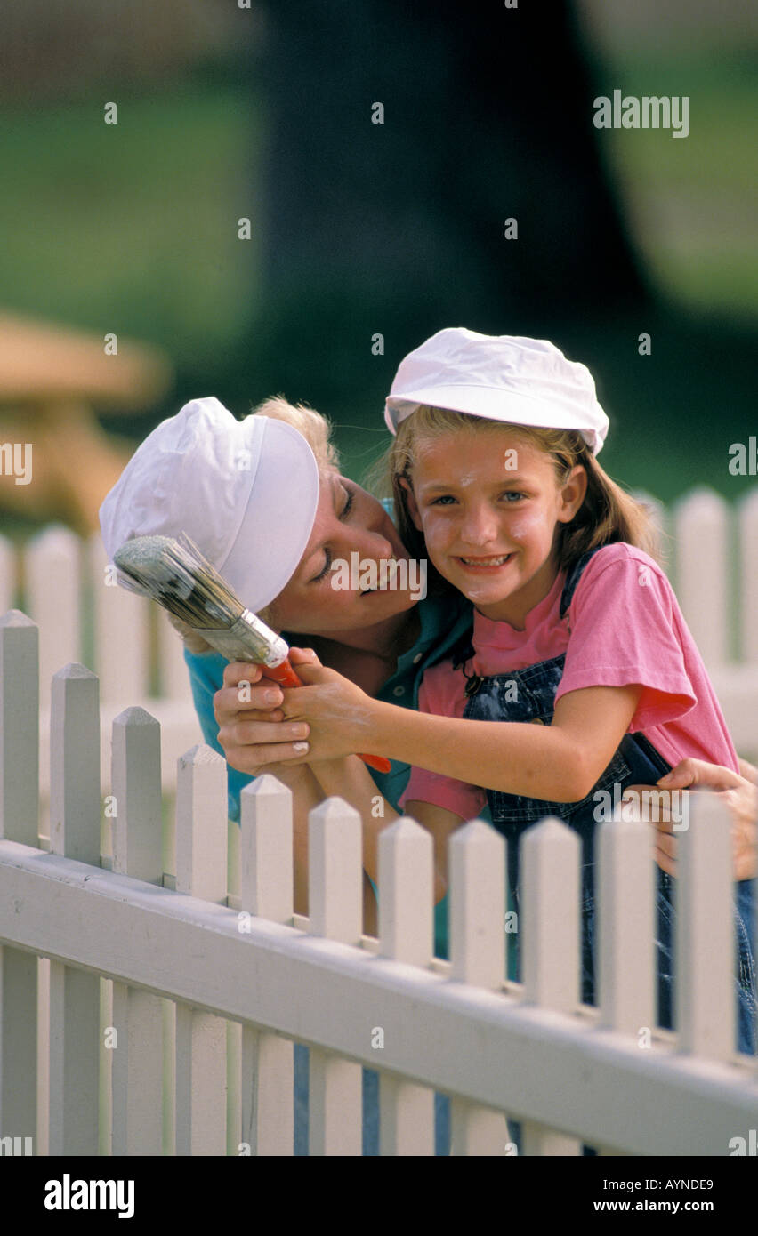 Kaukasischen Mutter und Tochter Malerei eine weiße Pickett Zaun Stockfoto
