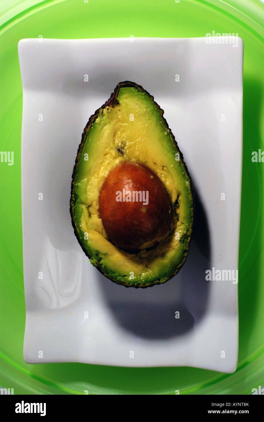 Avocado auf weißen Teller auf einem grünen Hintergrund Essen Stockfoto