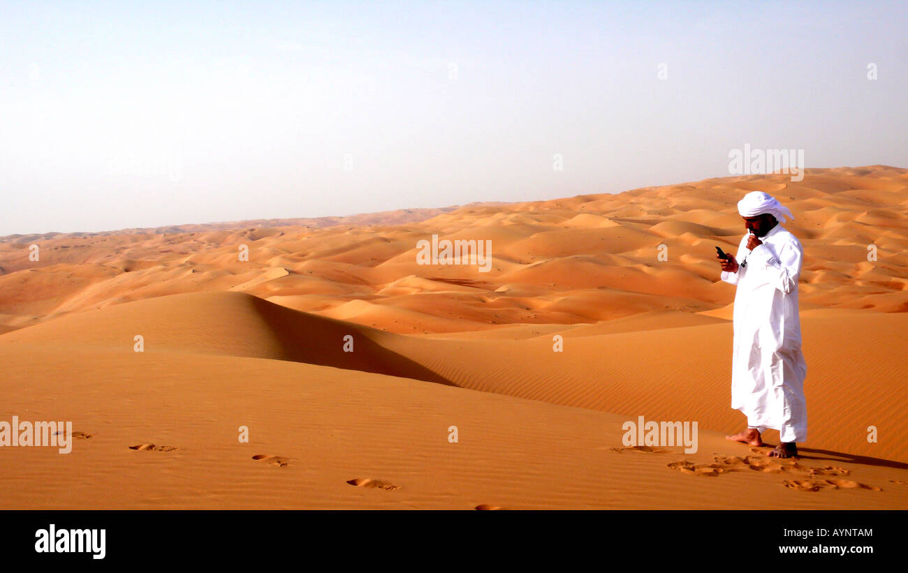 Ein Reiseleiter benutzt sein Telefon in der abgelegenen Liwa Wüste der VAE. Stockfoto