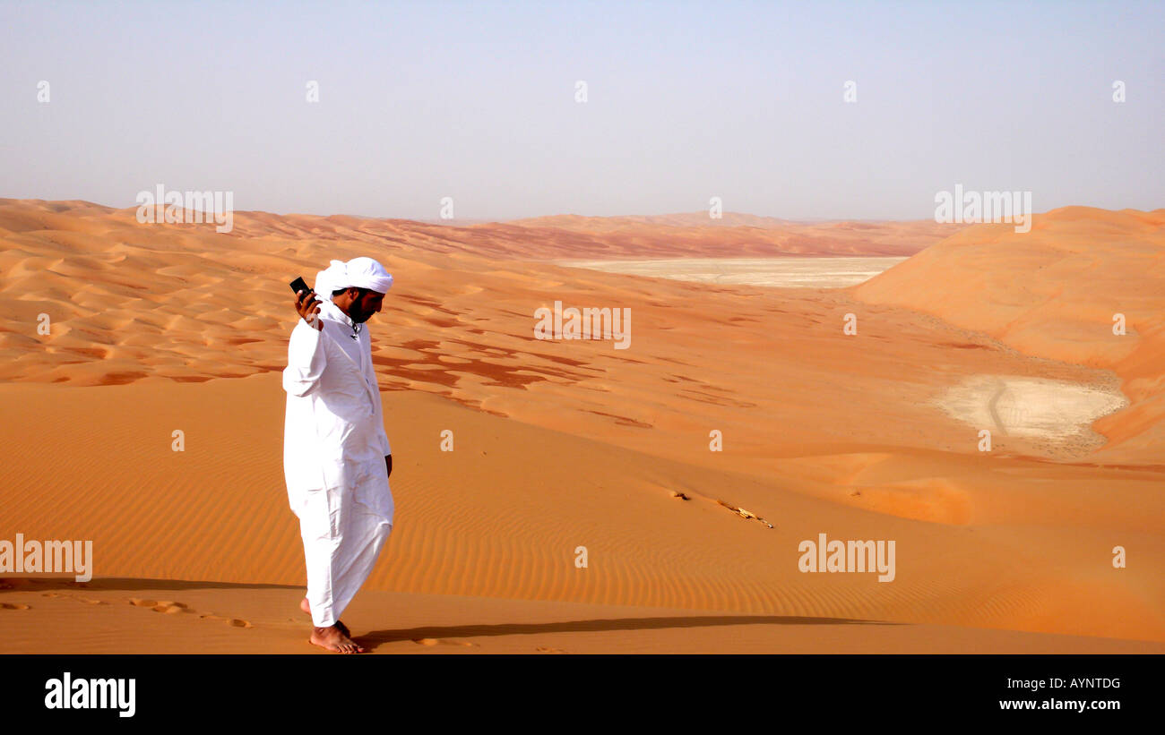 Ein Reiseleiter benutzt sein Telefon in der abgelegenen Liwa Wüste der VAE. Stockfoto