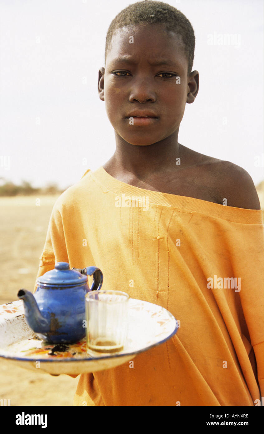 Kleiner Junge serviert Tee am Straßenrand, Douentza, Mali, Westafrika Stockfoto
