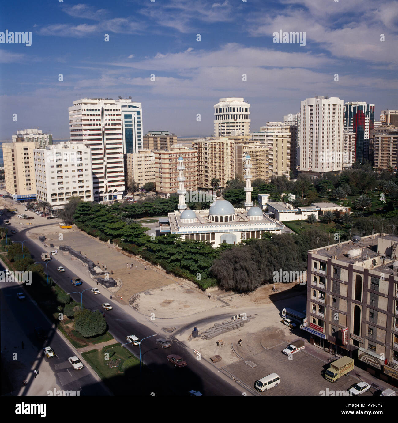 Vereinigte Arabische Emirate Abu Dhabi Nahost Golf Zustand erhöhten Blick über Moschee umgeben von Bäumen und hohen Aufstieg Gebäude neben einer Straße. Stockfoto