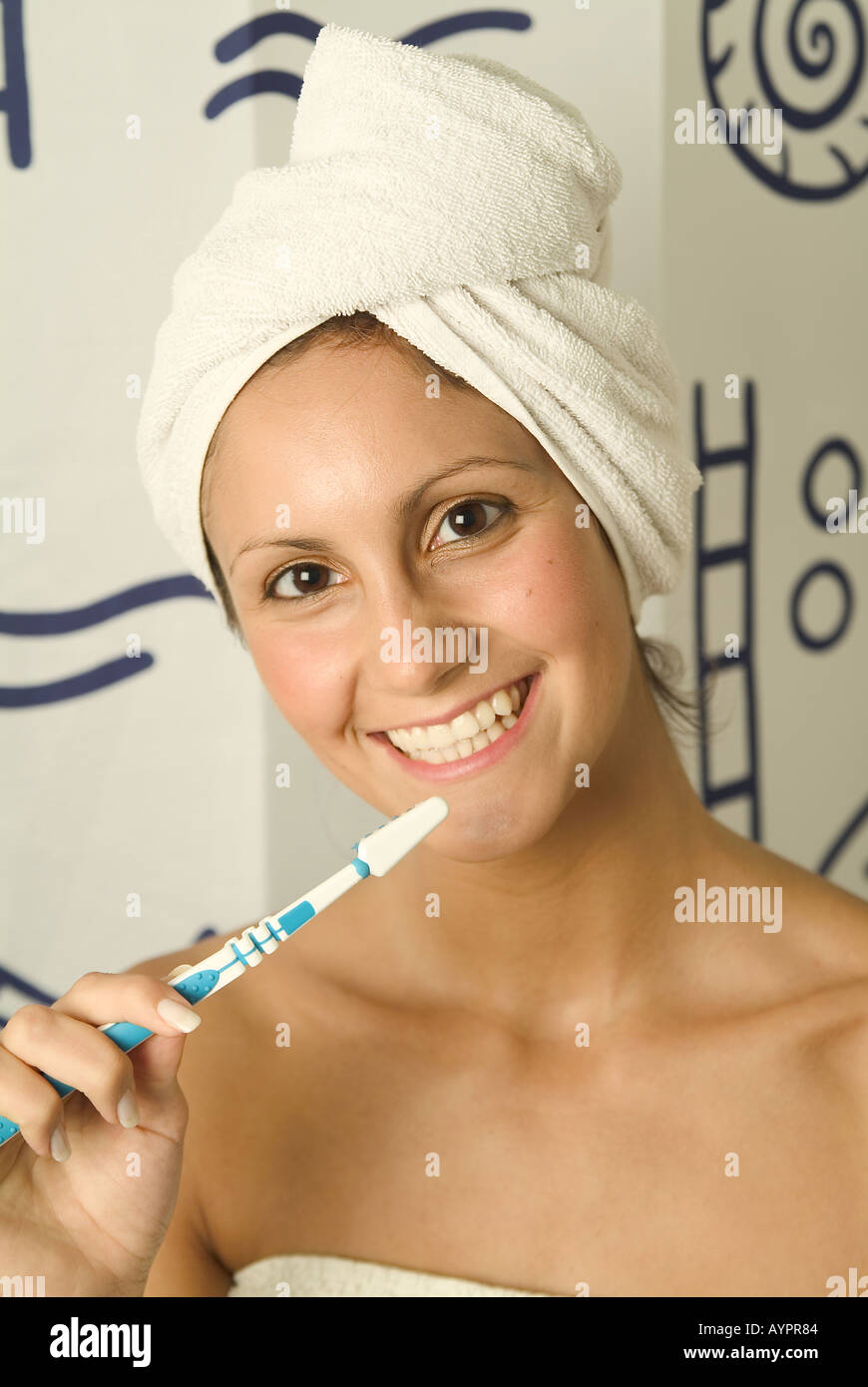 Eine junge Frau hält eine Zahnbürste, während sie ein breites Lächeln vor der Kamera gibt Stockfoto