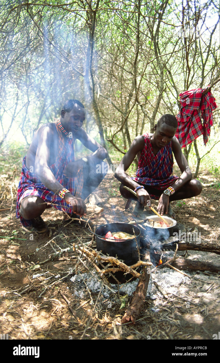 Junge, unverheiratete Maasai-Männer, die auf einem offenen Holzfeuer eine Mahlzeit mit Ziege und Gemüse kochen, bei Kajiado, Kenia Stockfoto