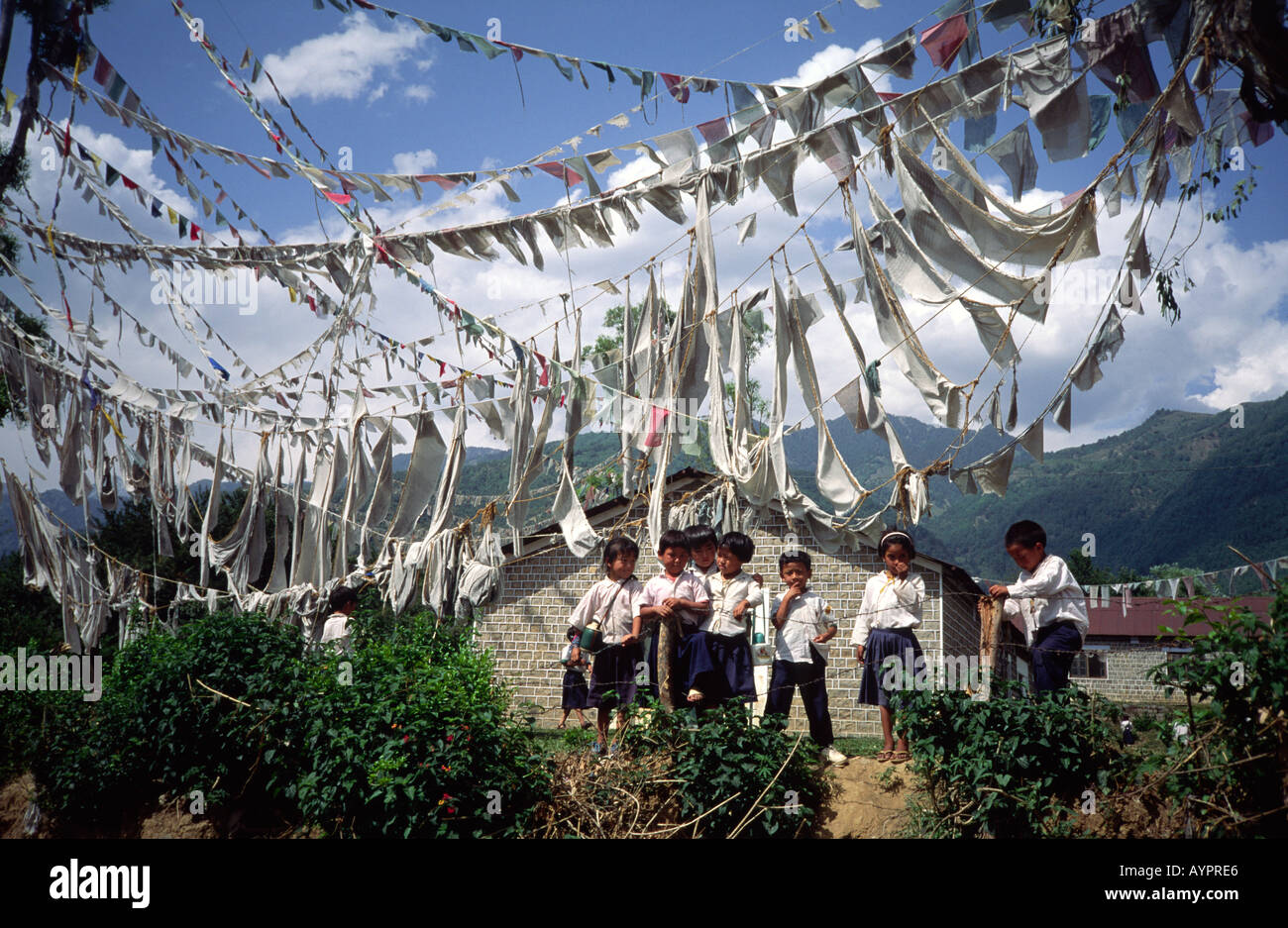 Tibetische Flüchtlingskinder außerhalb ihrer Schule unter Gebetsfahnen. Himachal Pradesh, Indiaopportunity Stockfoto