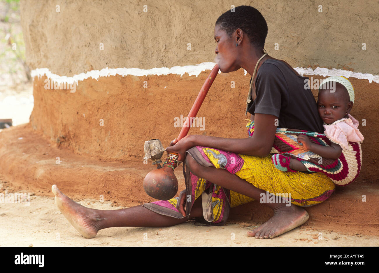 Batonga Frau sitzt in einer ländlichen Gesundheitsklinik, Baby auf dem Rücken, raucht eine traditionelle Gourd-Wasserleitung. Nr Binga, Simbabwe Stockfoto