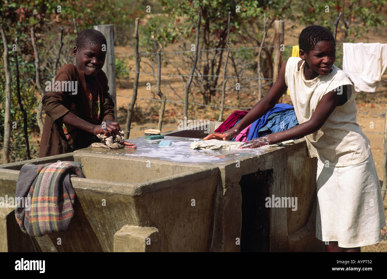 Zwei Mädchen waschen Kleidung an der örtlichen Wasserpumpe und am Waschtisch. Nr. Zaka, Simbabwe Stockfoto