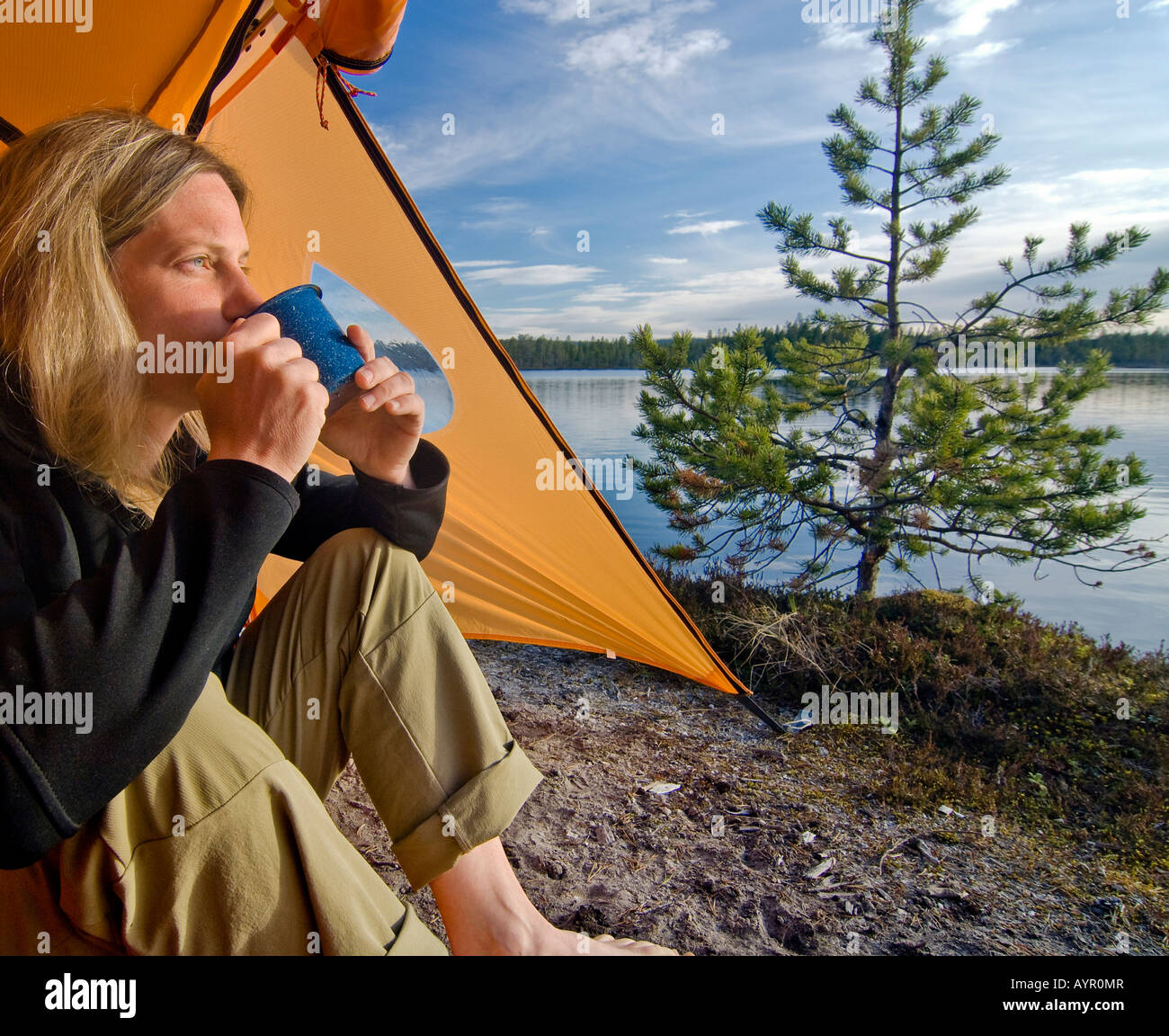 Frau sitzt vor einem Zelt, Blick in die Ferne und trinken aus einer Tasse, Femundsmarka Nationalpark, Femundsmark, Stockfoto