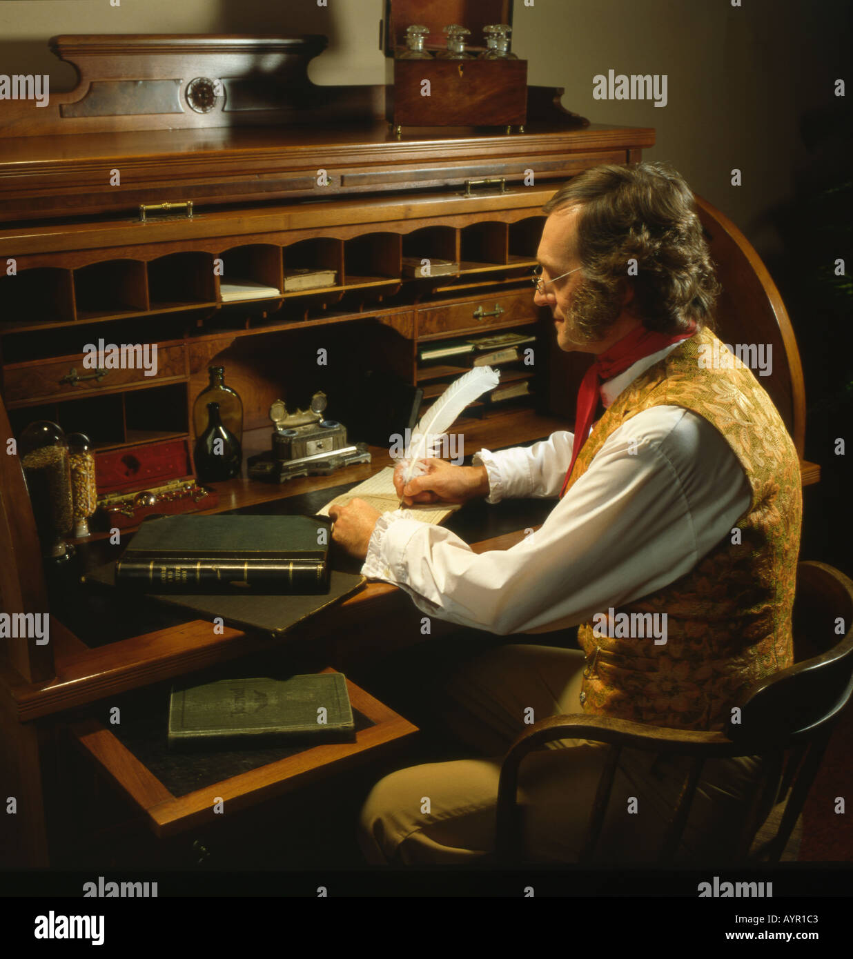 Mann im 19. Jahrhundert Kostüm sitzt am Roll Top Schreibtisch schreiben mit Feder Feder Stockfoto