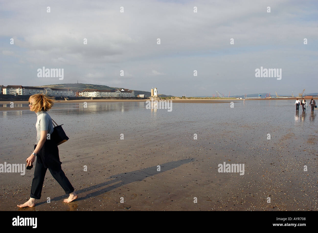 Frau zu Fuß auf nassen Swansea beach West Glamorgan Wales UK Stockfoto