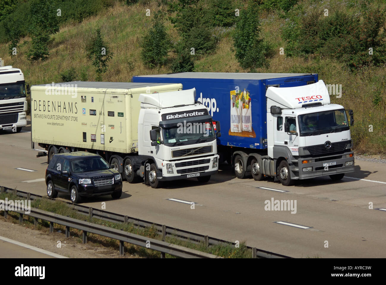 Debenhams und Tesco LKW mit Range Rover Auto überholen auf der Autobahn M25 Stockfotografie Alamy