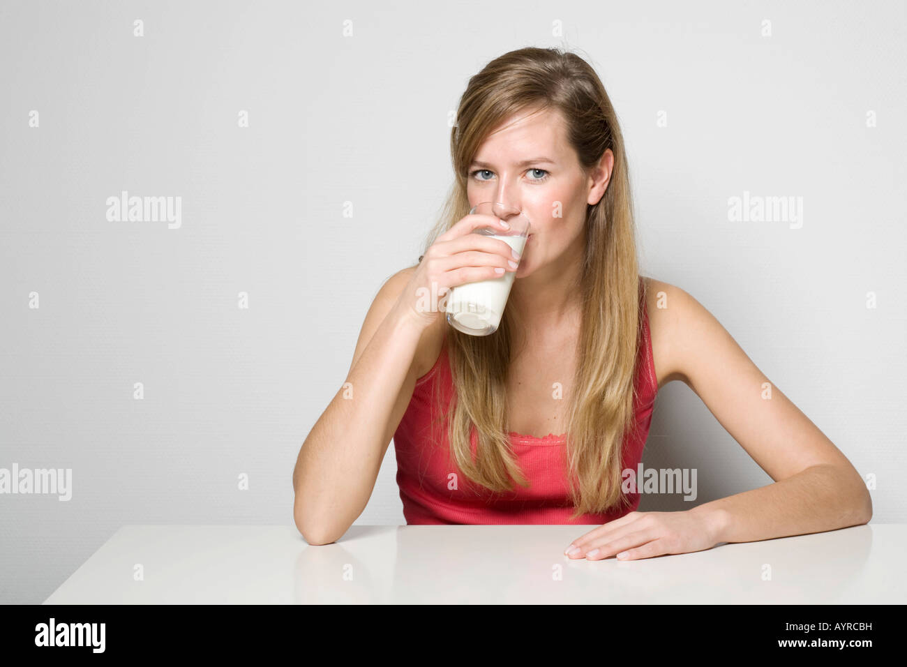 Junge Frau sitzt an einem Tisch ein Glas Milch trinken Stockfoto