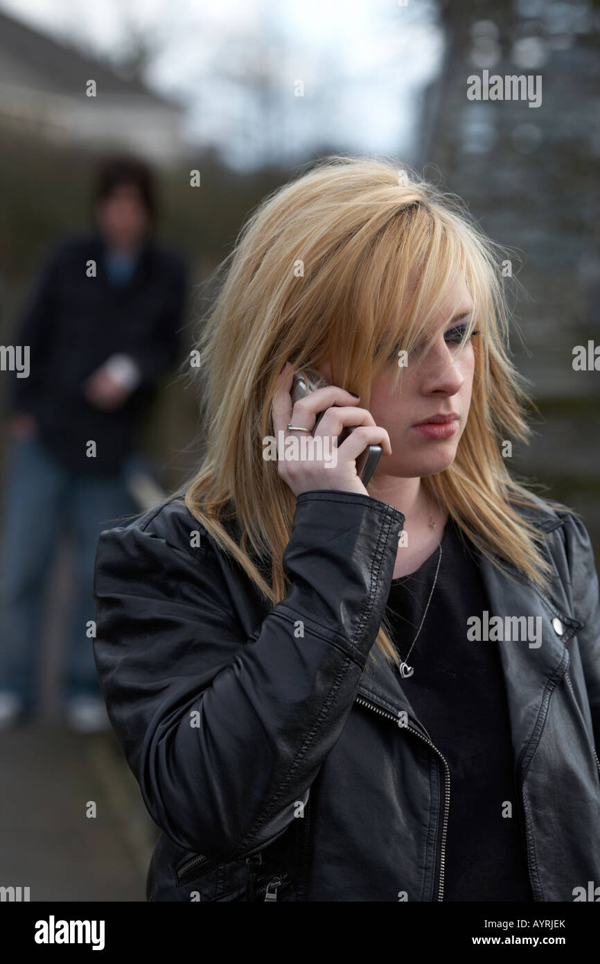 blonde behaarte Teenager Frau auf Handy telefonieren mit Mann stehend gerade stehend hinter schließen Stockfoto