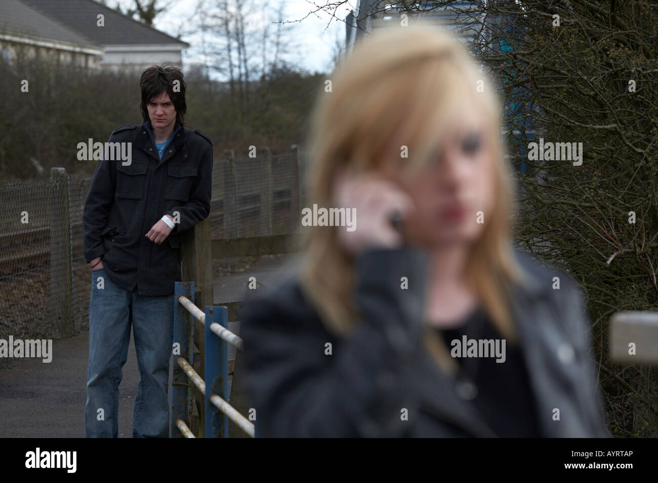 junger Mann beobachten blonde behaarte Teenager Frau auf dem Handy anrufen Stockfoto