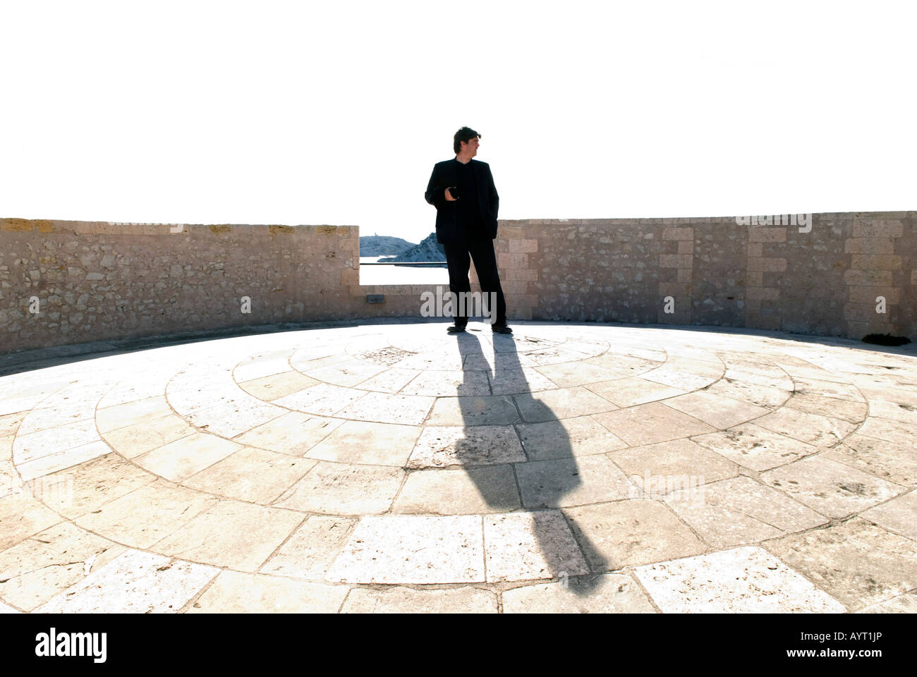 ein einsamer Mann im dunklen Anzug steht auf ein Kuppeldach des Chateau d in hellem Sonnenlicht Stockfoto