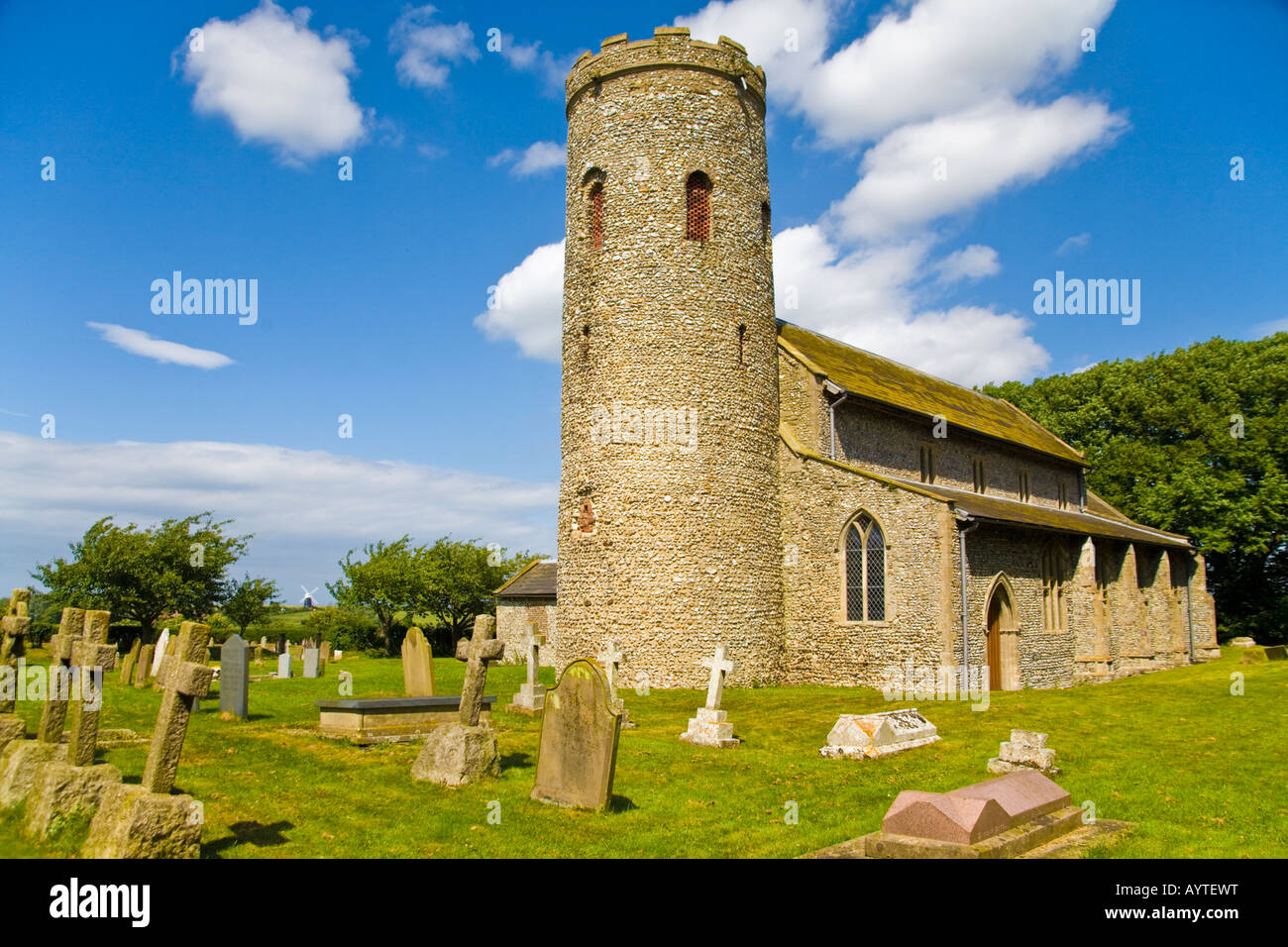 Historischen sächsischen runden Turm-Kirche an der Burnham Norton Norfolk in England mit Churchurchyard und Windmühle in Ferne Stockfoto