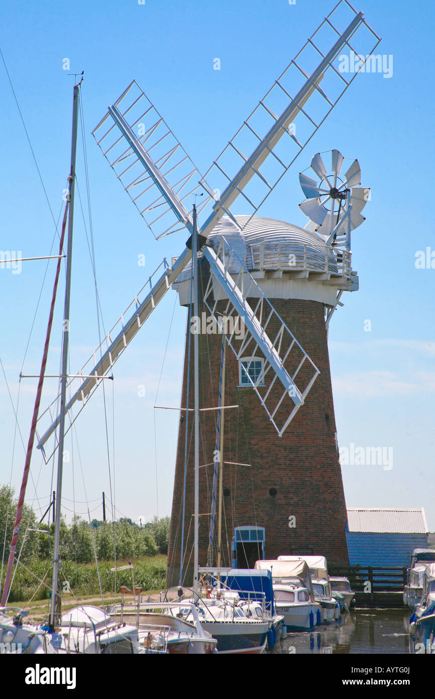 Kirche-Windpumpe bei Horsey Norfolk England zeigt Mühle und Boote am Fluss mit leuchtend blauen Sommerhimmel Stockfoto