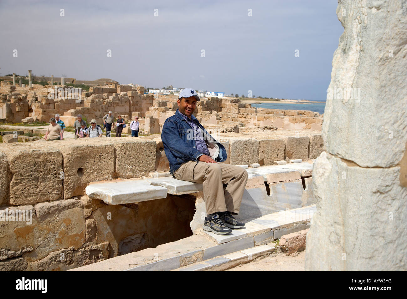 Touristen sitzen auf den Marmor-Latrinen in der antiken römischen Stadt Sabratha, Libyen Stockfoto