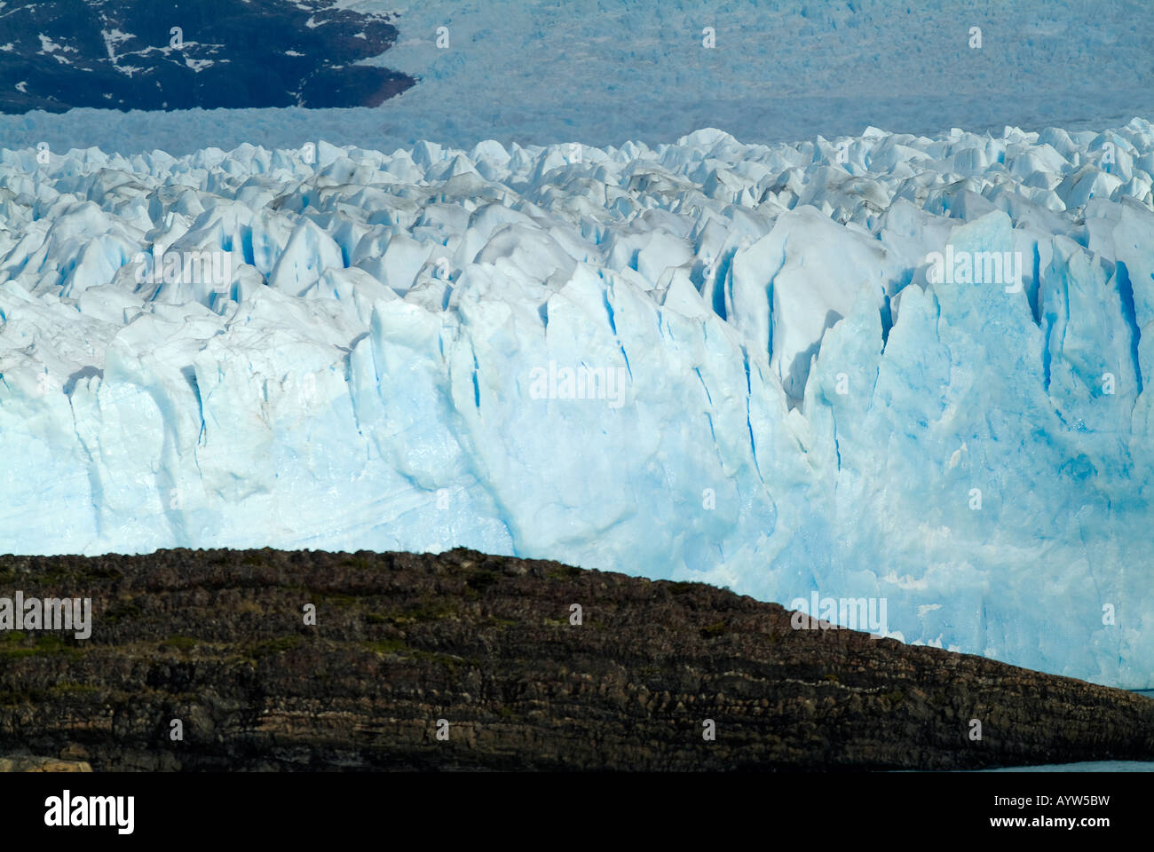 Eine Auffassung der Perito-Moreno-Gletscher, als es bewegt sich langsam vorwärts zu verschlingen die Granitfelsen im Vordergrund Stockfoto