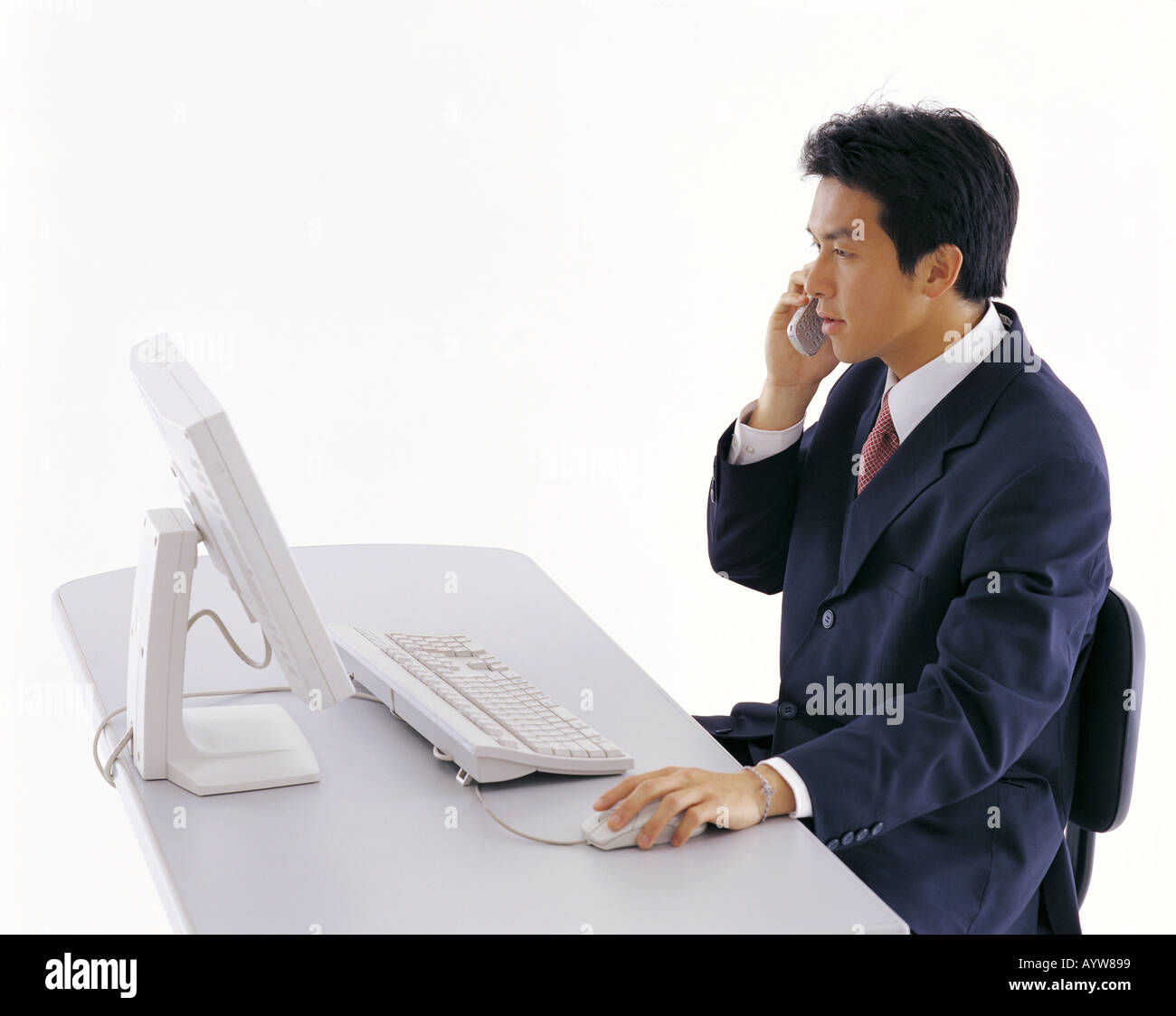 Büroangestellte, die auf einem Handy vor Computer sprechen Stockfoto