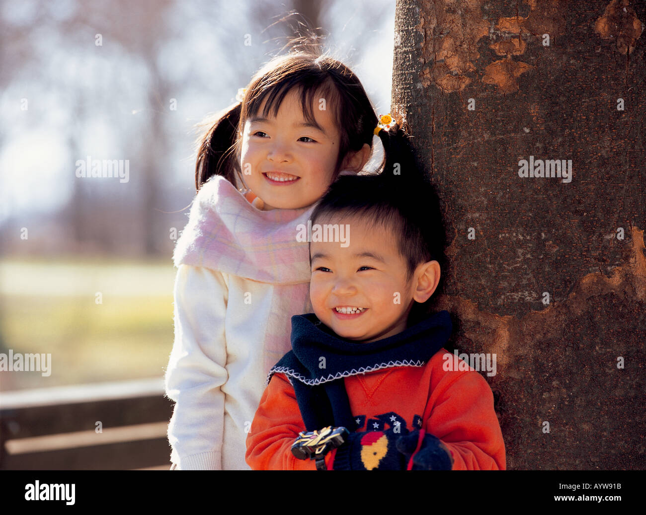 Mädchen mit ihrem Bruder von einem Baum stehend Stockfoto