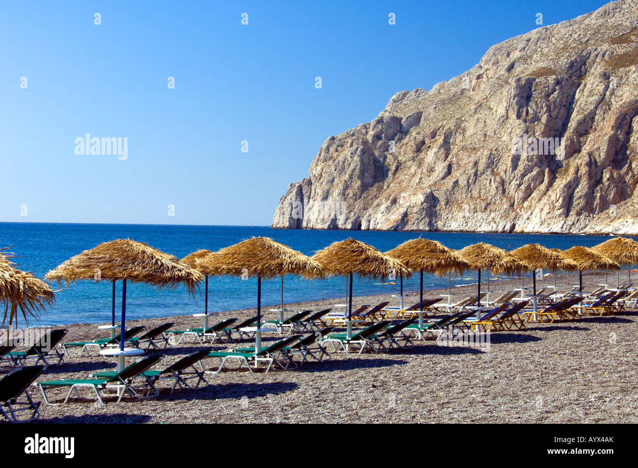 Die schwarzen Sandstrände mit Sonnenschirmen und Liegestühlen in Kamari auf der griechischen Insel Santorini Griechenland Stockfoto
