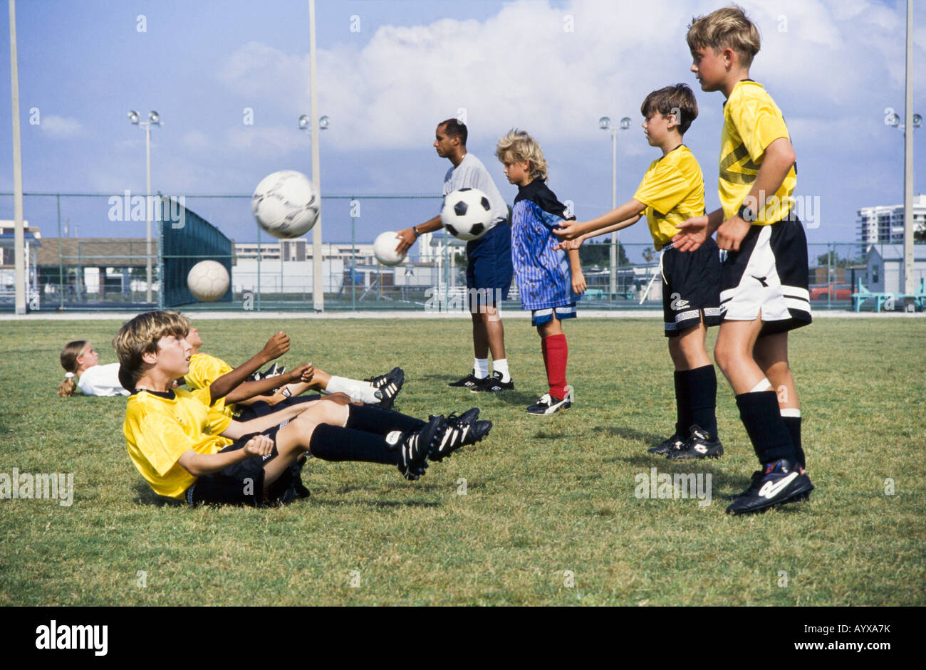 Kids Fußball-Team, Mädchen und Jungen gemeinsam mit Trainer unterrichten Fähigkeiten, Teamarbeit, Teamgeist, Melbourne, Florida Stockfoto