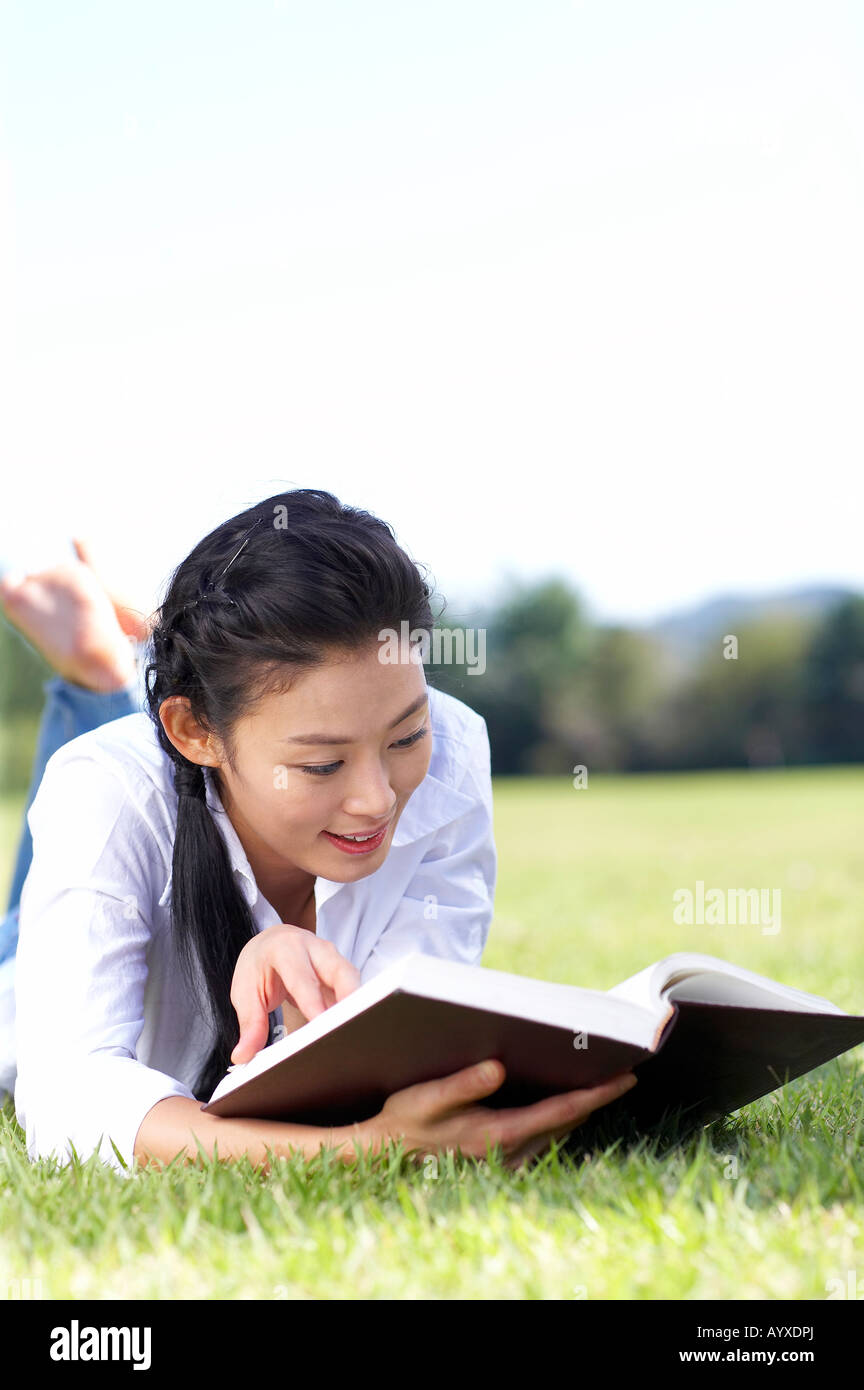 eine Frau liest ein Buch mit Festlegung auf der Wiese Stockfoto