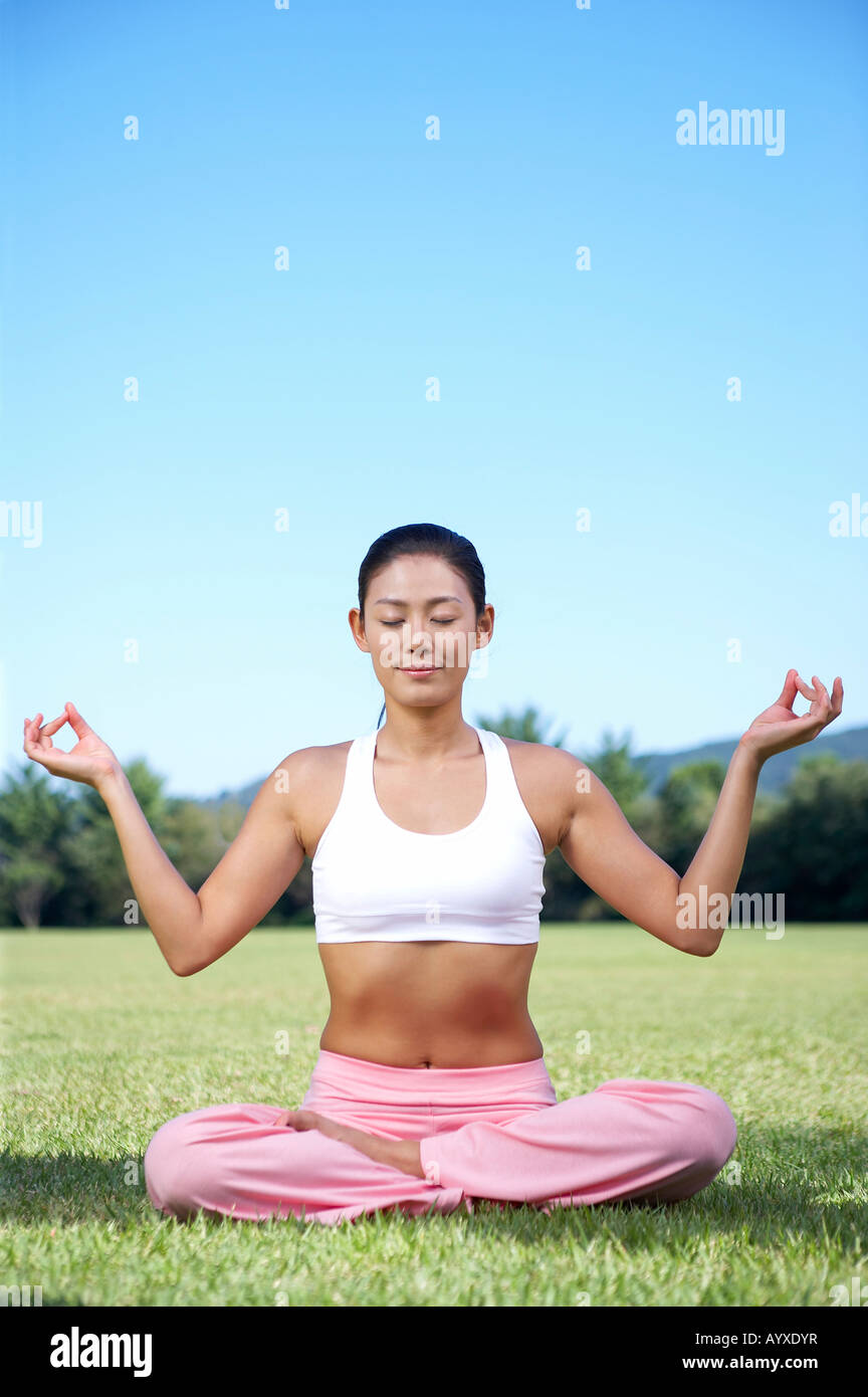 eine Frau auf Wiese mit deutete Yoga sittin Stockfoto