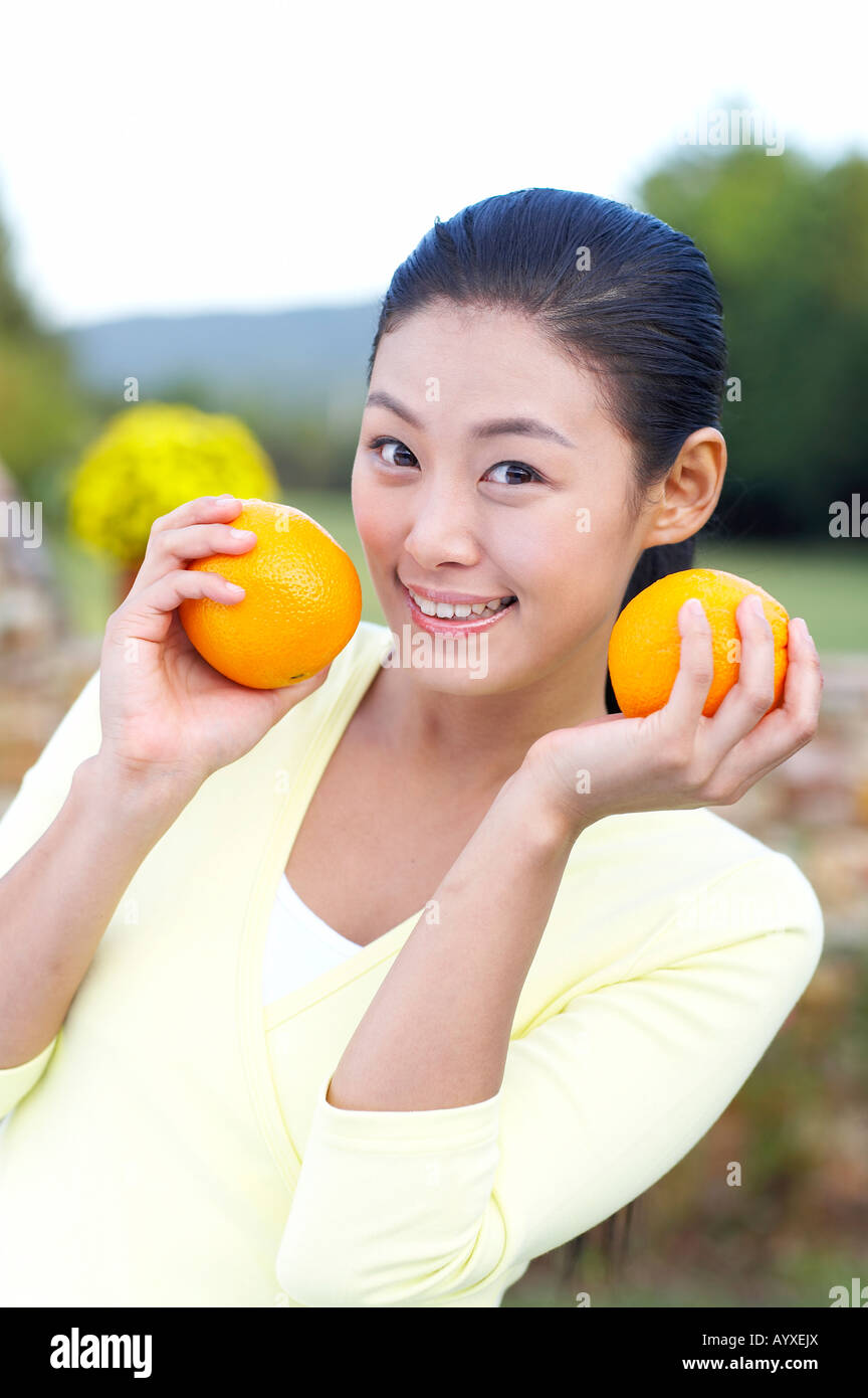 eine Frau lächelnd mit Orangen an den Handflächen halten Stockfoto