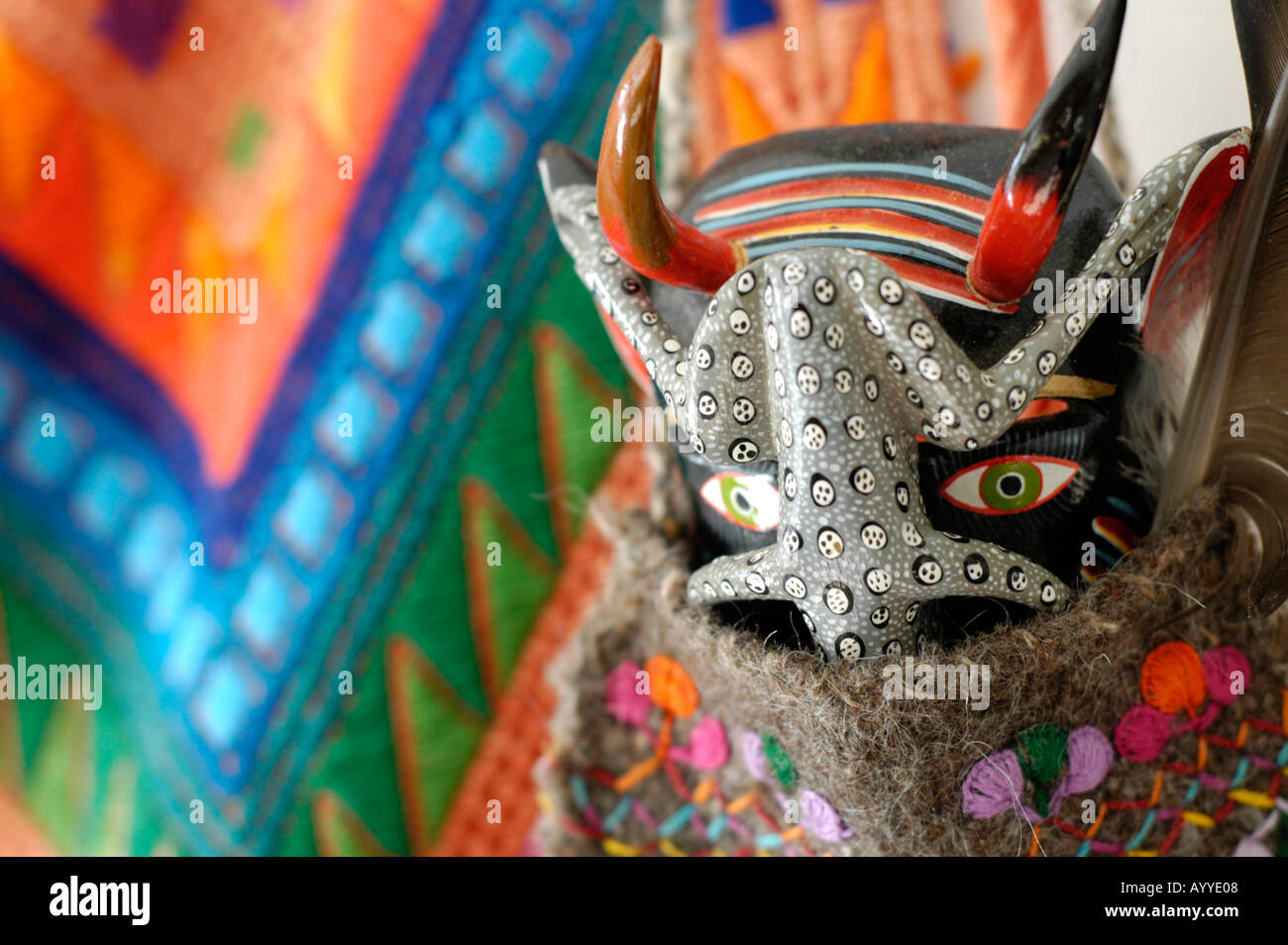 Teufel Maske aus Mexiko gegen ein guatemaltekischen Maya Huipil als Wandbehang hervorgehoben Stockfoto