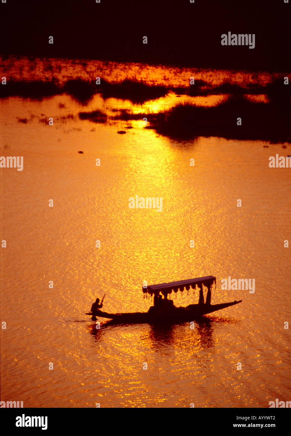 Ein ruderer Paddles mit dem Boot über den See Pichola bei Sonnenuntergang in Richtung Lake Palace Hotel in Udaipur, Rajasthan, Indien Stockfoto
