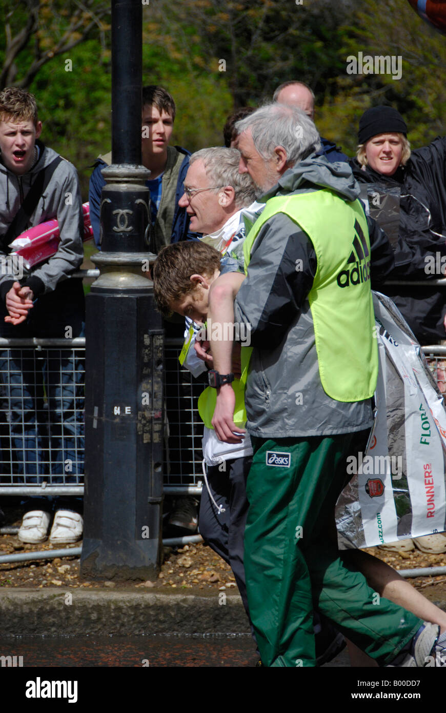 Zwei Stewards helfen erschöpft junge Läufer beim London-Marathon 2008 Stockfoto