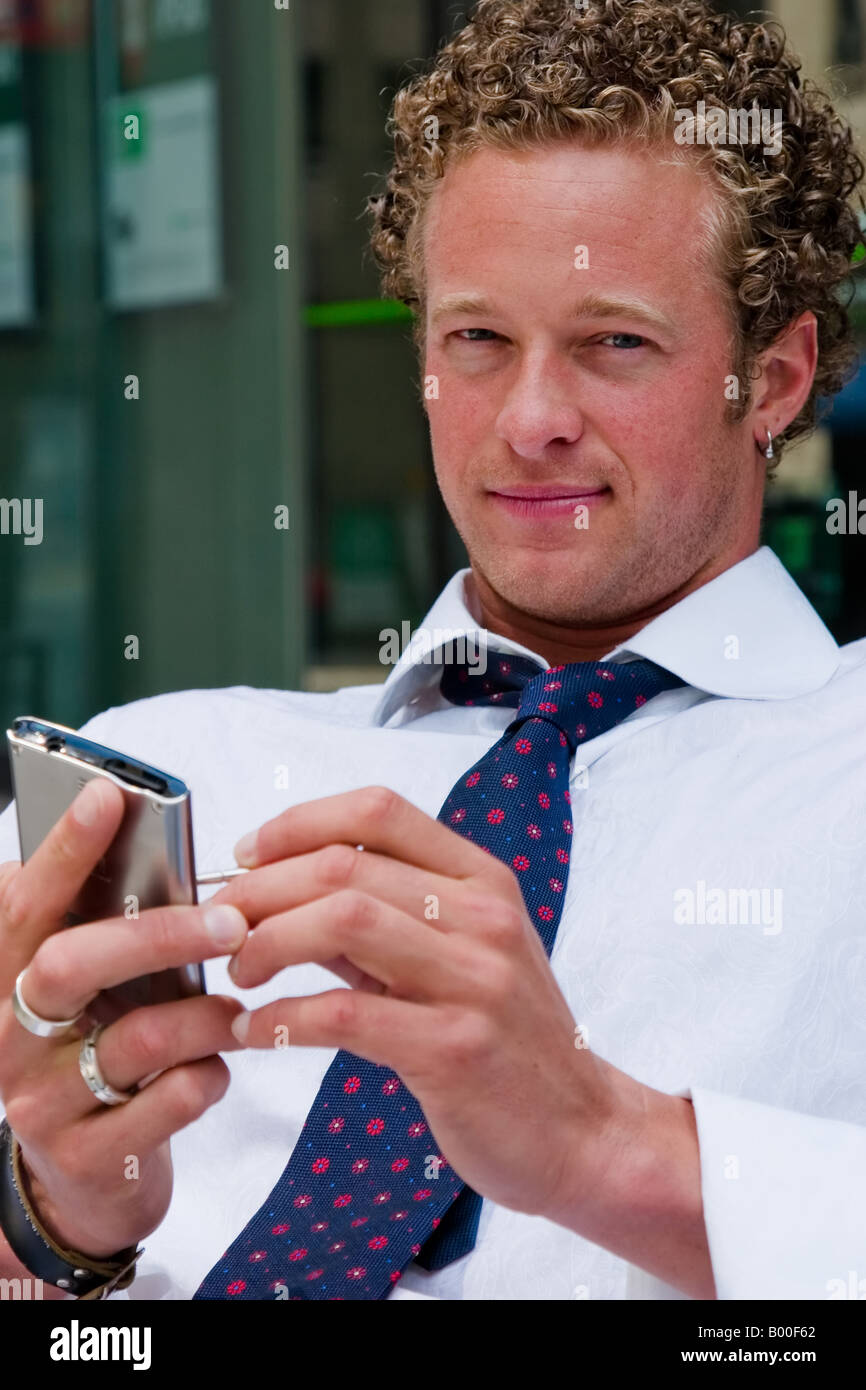 Ein junger Geschäftsmann arbeitet an seinem handheld Palm Pilot Stockfoto