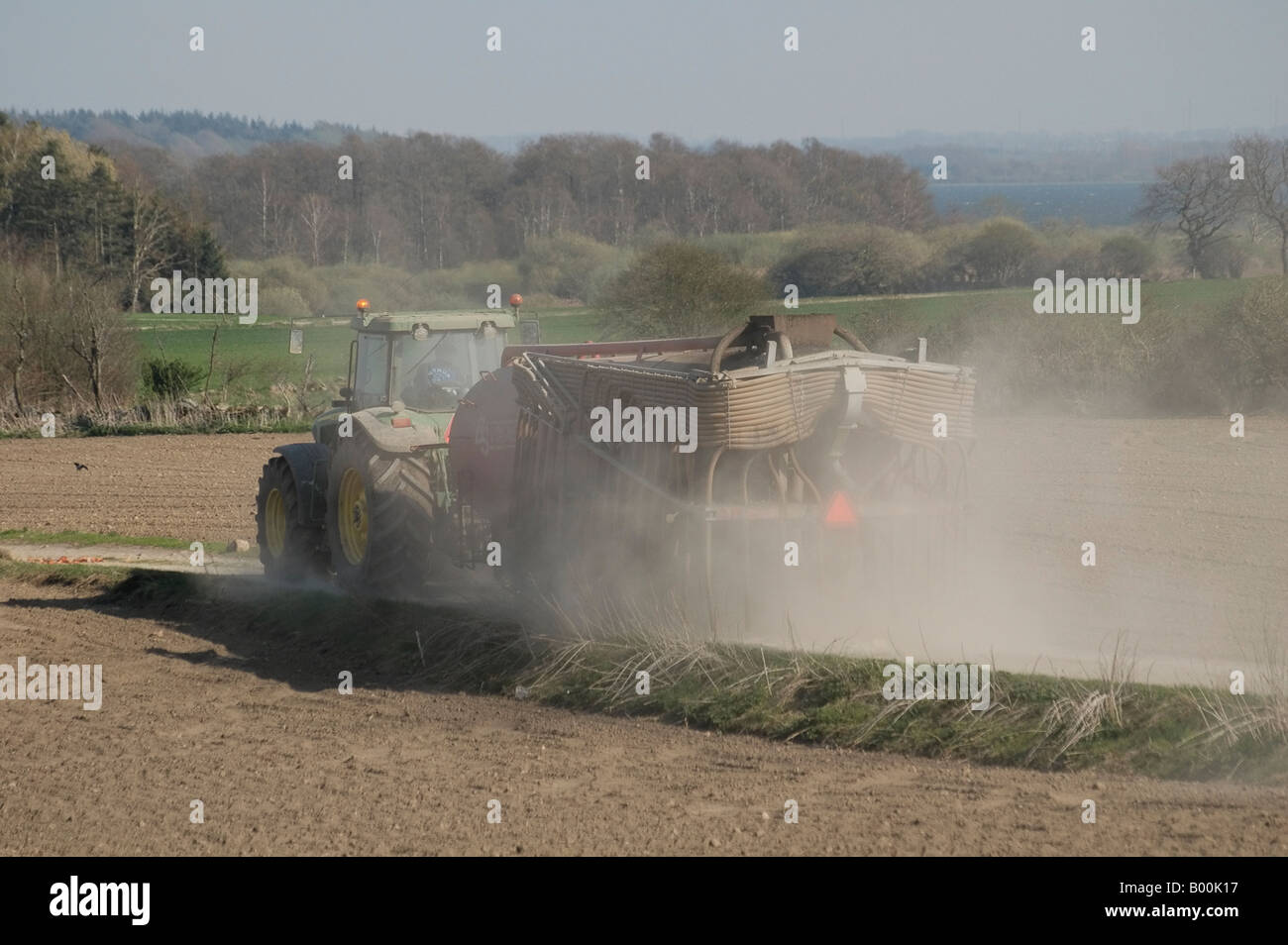 Kot verbreiten Traktor im Frühjahr, die Gülle auf den Feldern im zeitigen Frühjahr in Dänemark verbreitet ist Stockfoto