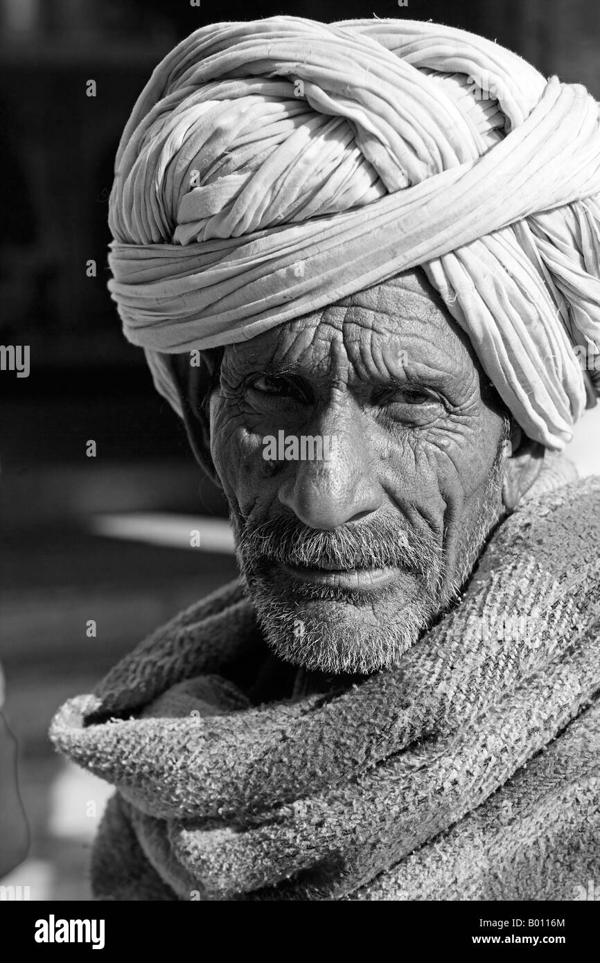 Indien, Rajasthan, Jaisalmer.  Auf dem Markt eine Standinhaber bündelt sich oben mit einem wollenen Schal um die Kälte abzuwehren. Stockfoto